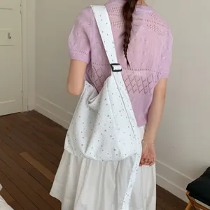 Back view of a model carrying a white canvas bag with glittering star patterns
