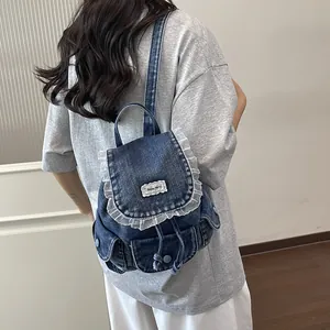 Dettaglio dello zaino vintage in denim con bordo in pizzo bianco ed etichetta Beyou Merci.