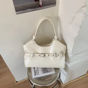 Minimalist cream underarm tote bag featuring decorative belt detail shown on metal stool
