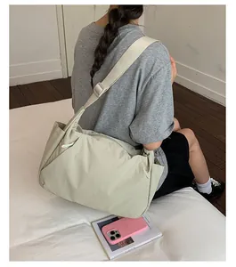 Side view of a large lightweight nylon tote bag worn by a model sitting on a bed