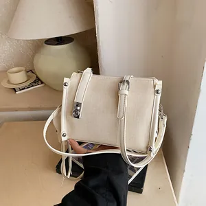 Detail of cream canvas pillow bag with silver hardware and adjustable strap