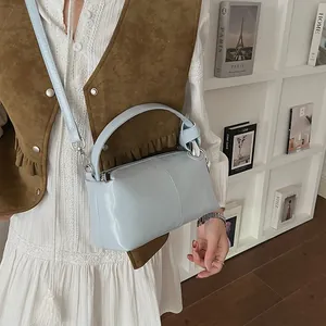 Light blue retro pillow bag styled with a white dress and brown vest