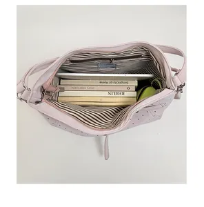 Interior detail of large capacity pink polka dot tote bag showing books and tablet