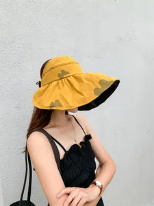 Stylish yellow sun hat with butterfly print and black vinyl lining for UV protection.