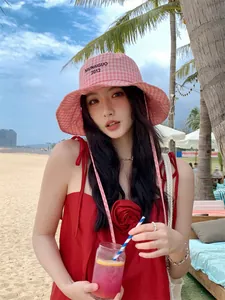 Dettaglio di un cappello da pescatore a scacchi rosa con ricamo e tesa larga in spiaggia