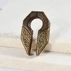 Détail d'un poids d'oreille en forme de U avec gravure dorée et texture bois.