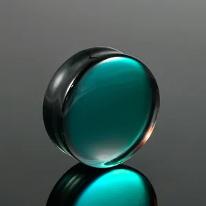 Close-up of polished solid teal glass ear expander plug with reflective finish