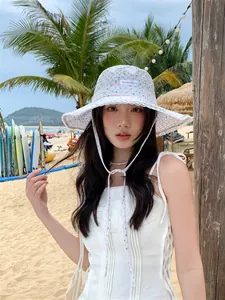 Elegant floral lace bucket hat with wide brim and chin strap in a sunny beach setting