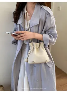 Chic cream-colored pebbled leather drawstring bucket bag for women, minimalist retro style.