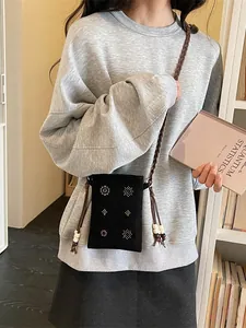 Retro black velvet crossbody phone bag with beaded floral patterns shown worn by a model