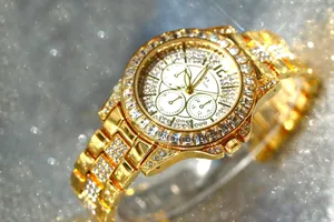 Detailed view of luxury gold women's watch featuring sparkling square crystal bezel