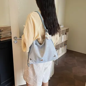 Detailed lifestyle view of a light blue large capacity bag with butterfly embroidery
