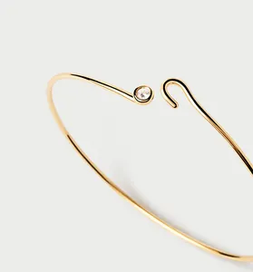 Détail d'un bracelet jonc en argent doré minimaliste avec fermoir crochet et pierre claire