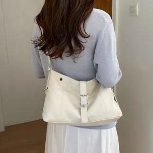 Trendy cream-white leather underarm tote bag worn by a model in a minimalist setting