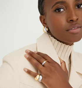 Professional detail shot of model wearing two-tone sterling silver glossy rings and earrings