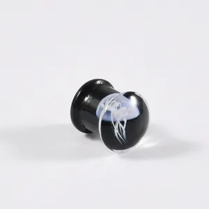 Detaillierte Nahaufnahme eines schwarzen Glas-Ohrstöpsels mit weißem Quallendesign