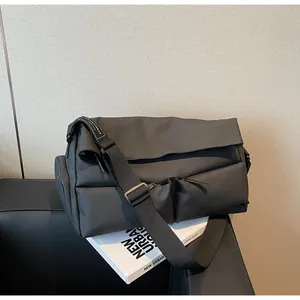 Detailed view of a black multi-pocket urban sports messenger bag on a studio prop