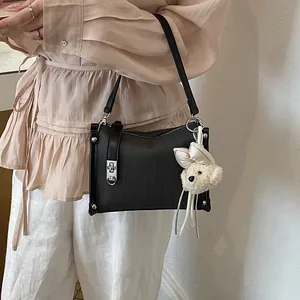 Macro view of a stylish black women's pillow handbag with a cute cream bear charm decoration