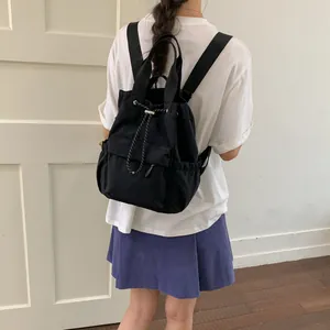 Vista posterior de una persona con mochila negra de cordón y bolsillos laterales