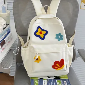 Detailed view of cream canvas school backpack featuring colorful plush flower embroidery accents