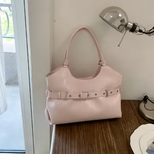 Stylish soft pink leather tote bag featuring decorative buckle detail on a rustic wooden desk