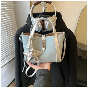 Detailed close-up of light blue denim bucket bag with sparkling studs and silver star charm