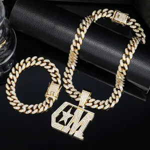 Detailweergave van de gouden CM hanger ketting en bijpassende Cubaanse schakelarmband.