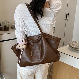 Grote bruine tote bag met strik en pluche hanger gedragen op de schouder