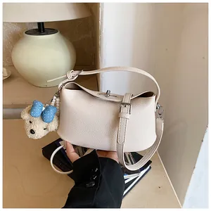 Close-up detail of cream textured faux leather bucket handbag featuring a cute bear charm