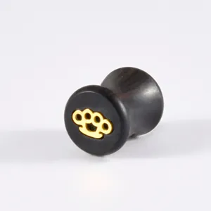 Close-up of ebony wood ear gauge plug with gold brass knuckle inlay pattern detail.