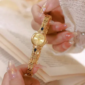 Primer plano detallado de un reloj de cadena dorado vintage con circones azules para mujer