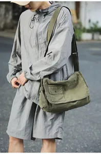 Olive green canvas messenger bag styled on model in casual urban street setting
