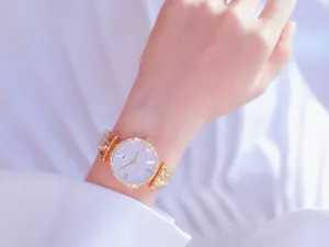 Primer plano de un lujoso reloj de mujer en oro con esfera de diamantes efecto cielo estrellado