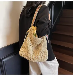 Vue de dos d'une femme portant un sac cabas en paille tissée avec une bandoulière
