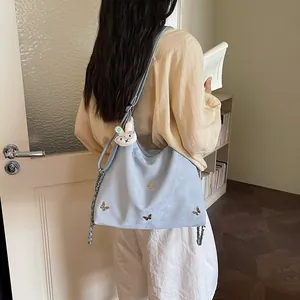 Lifestyle view of a large blue commuter bag with butterfly embroidery and rabbit charm.