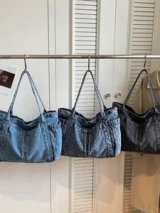 Sacs fourre-tout en denim vintage en trois délavages suspendus sur un support de mode.