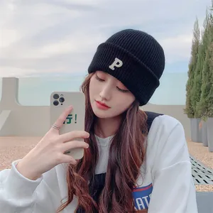 Stylish model wearing a black knitted beanie with white letter P embroidery detail