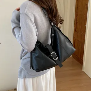 Close-up of stylish black faux leather hobo bag with silver buckle worn by a model