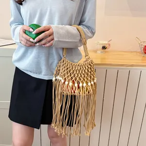 Summer woven macrame handbag with long fringes and bead details held by a model