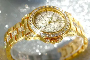 Close-up of a luxury gold women's watch encrusted with sparkling clear rhinestones