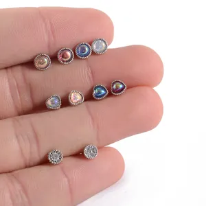 Detail view of various iridescent heart and round CZ stud earrings displayed on fingers