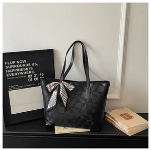 Elegant black tote bag with geometric pattern and scarf detail in a lifestyle setting