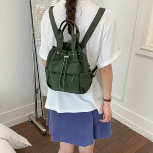 Vista trasera de una mujer con una mochila con cordón verde oscuro en una habitación luminosa
