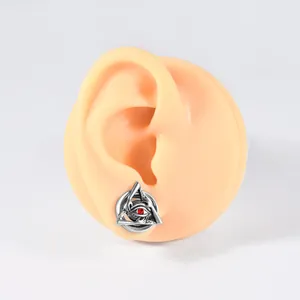 Macro detail of stainless steel ear plug featuring a triangle eye design with a red stone