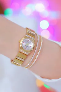 Detail van een klein gouden dameshorloge met twee elegante sprankelende strass-armbanden