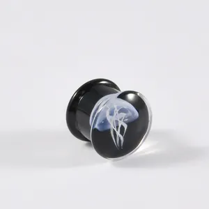 Detailansicht eines filigranen weißen Quallendesigns in einem schwarzen Glas-Ohrdehner-Plug.