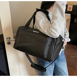 Large black fitness travel duffel bag carried by a person in a modern indoor setting