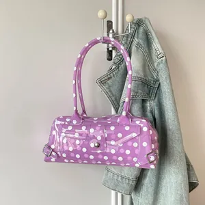Stylish purple polka dot PVC transparent baguette shoulder bag hanging on a wall hook