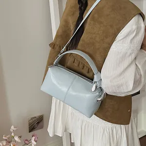 Light blue glossy vintage pillow bag worn with a white dress and brown suede vest