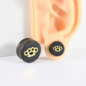 Close-up view of black ebony wood ear plug featuring a golden knuckle duster pattern inlay